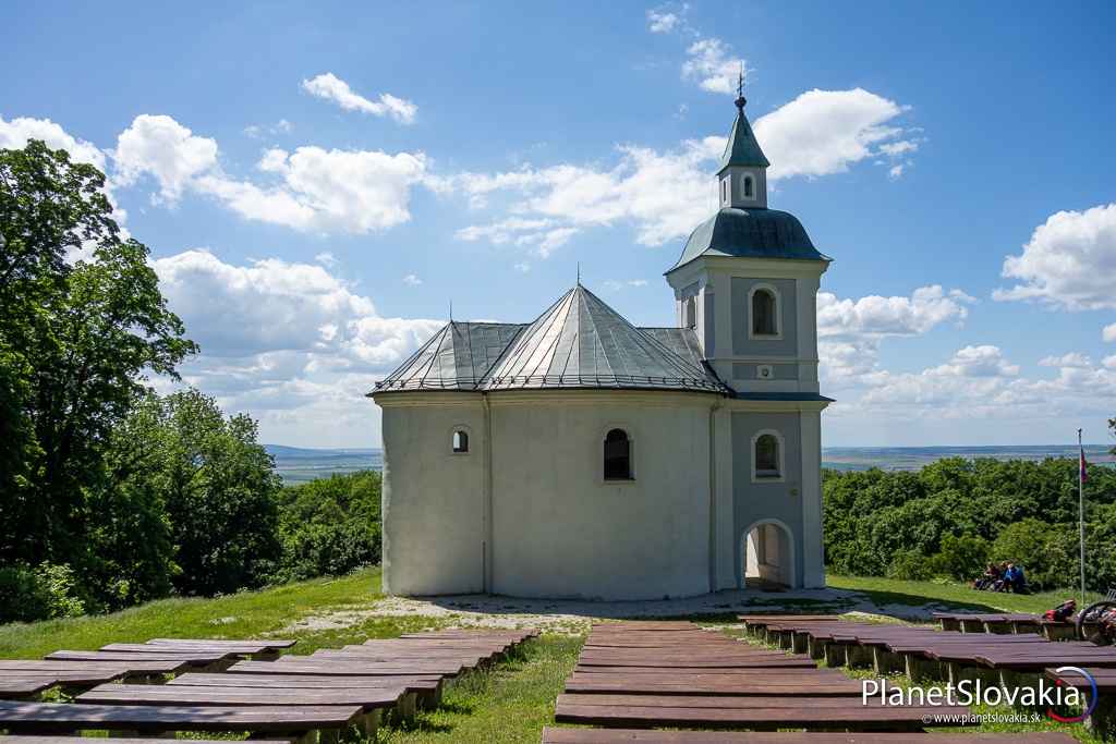 Pohľad na Rotundu svätého Juraja z amfiteátra s drevenými lavicami.