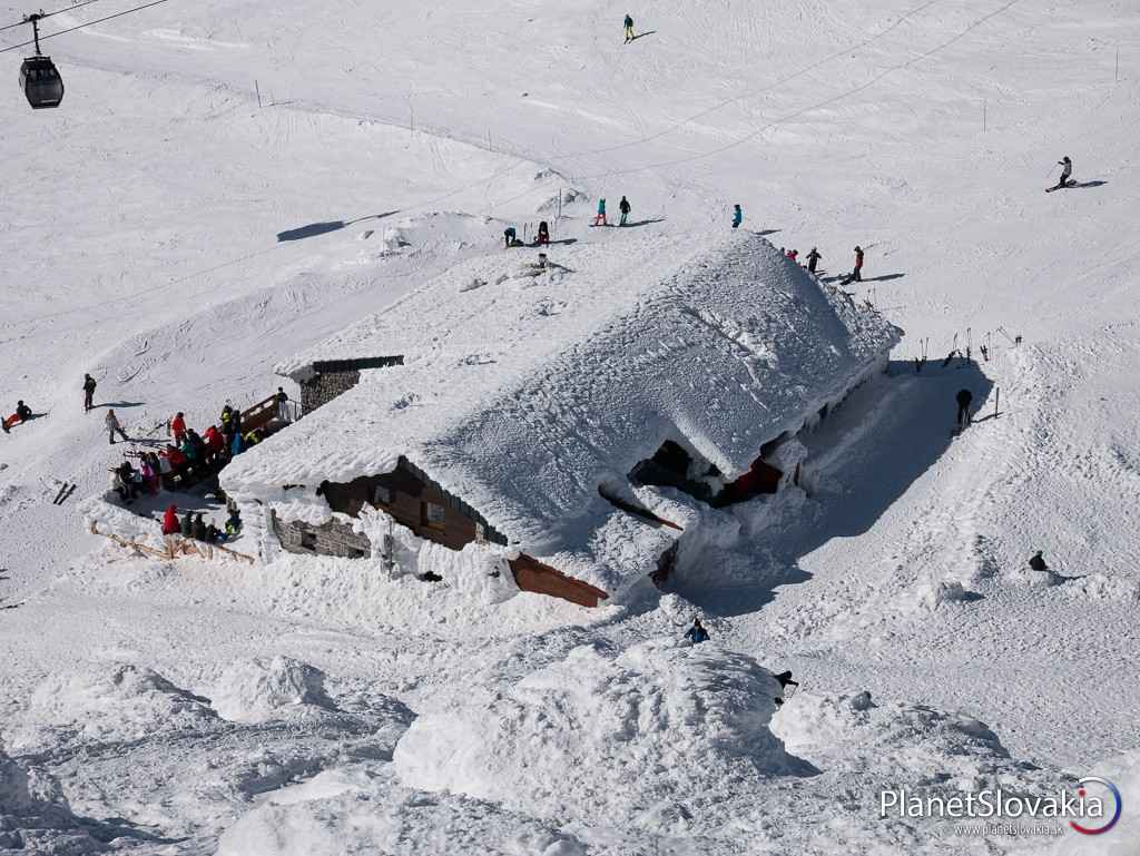 Pohľad na Kamennú chatu zo západných svahov Chopka. Táto chata patrí k hlavným útočiskám pre turistov na hrebeňovke Nízkych Tatier.