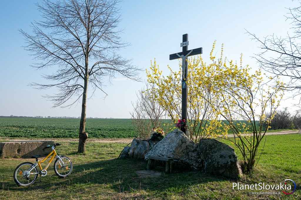 Po prejdení krátkej rokliny Glanec si môžete okrem kamenných tvári pozrieť i tento kríž a miestne polia.