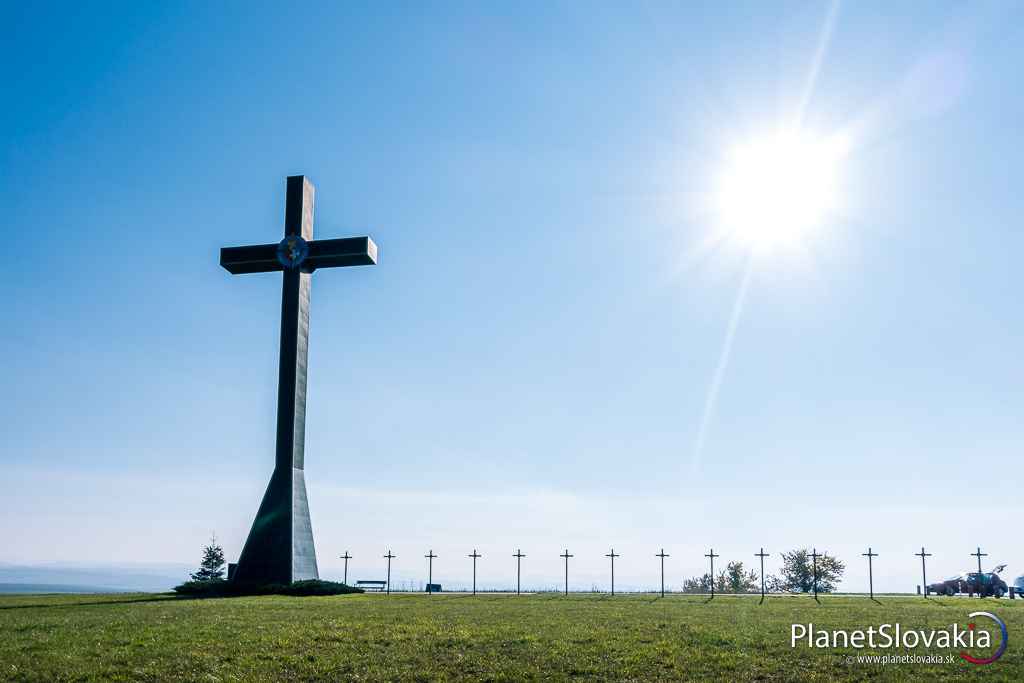 V lúčoch slnka. Miléniový kríž leží na otvorenej lúke, nechránený pred prírodnými živlami